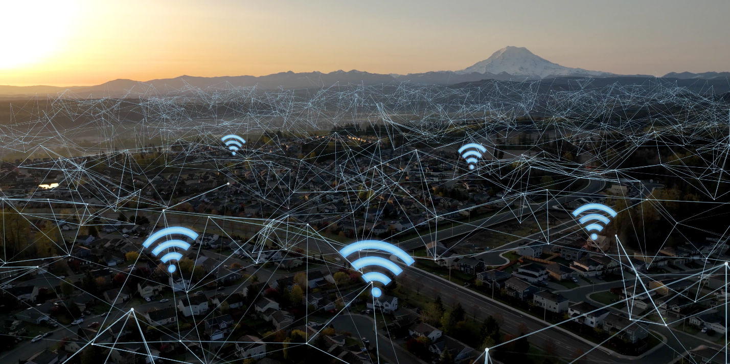Aerial view of a small town representing what is a home network system, with sunset, mountains, connectivity lines, and Wi-Fi icons in the neighborhood.
