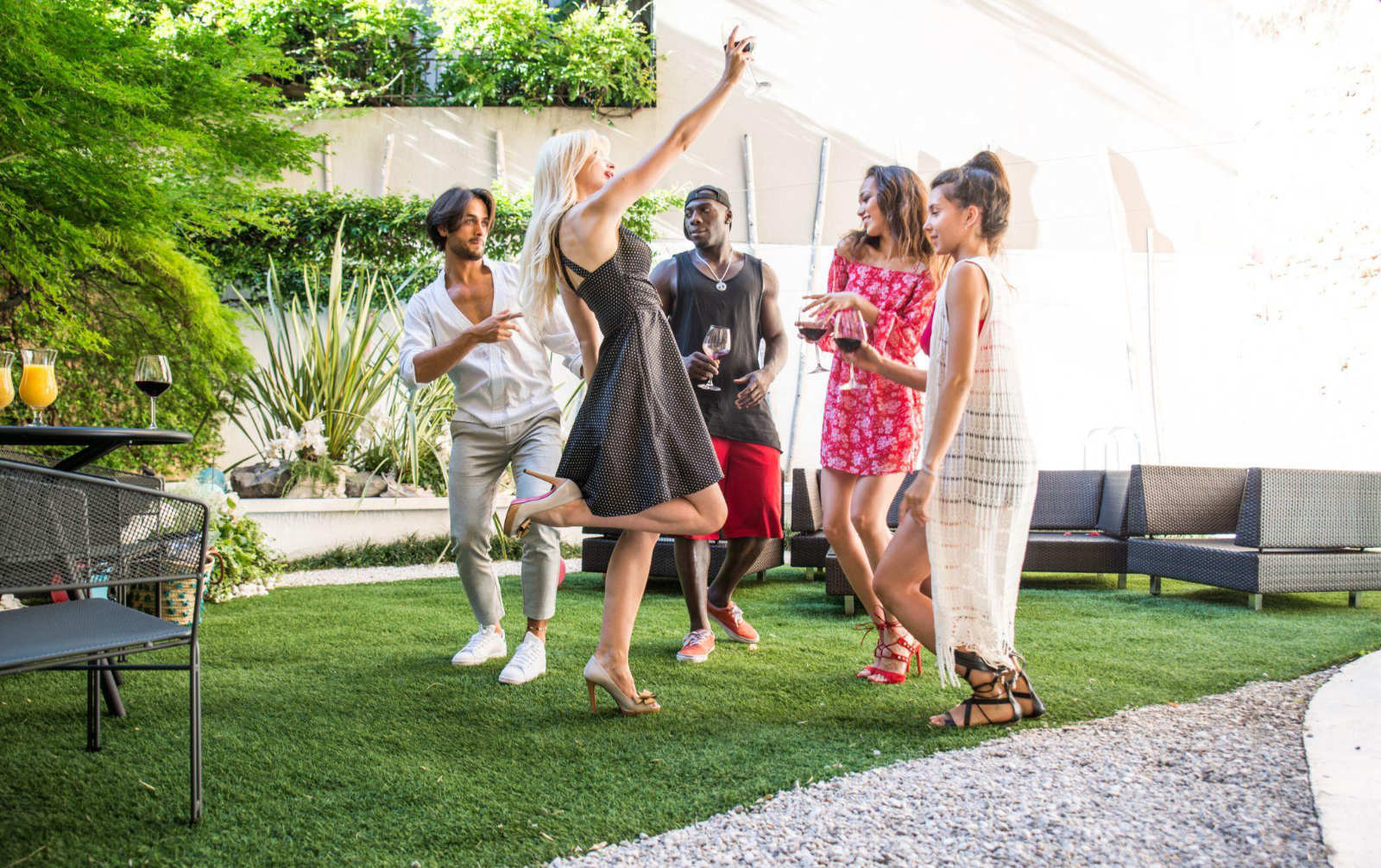 Friends dancing on a backyard lawn during a party powered by a high-performance outdoor sound system.