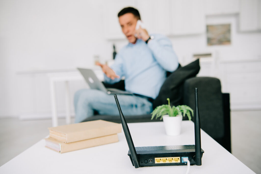 man blurred in the background upset about the internet, in focus is the modem / router